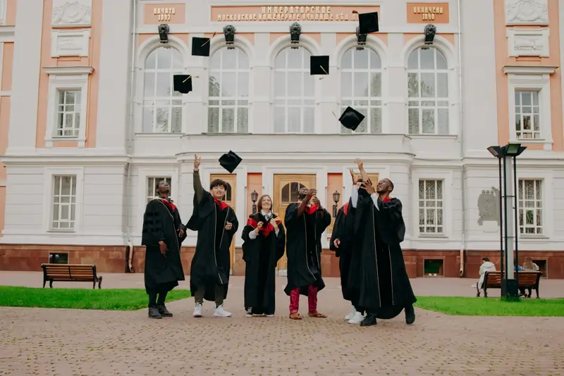 Graduates throwing their caps in the air outside a university building